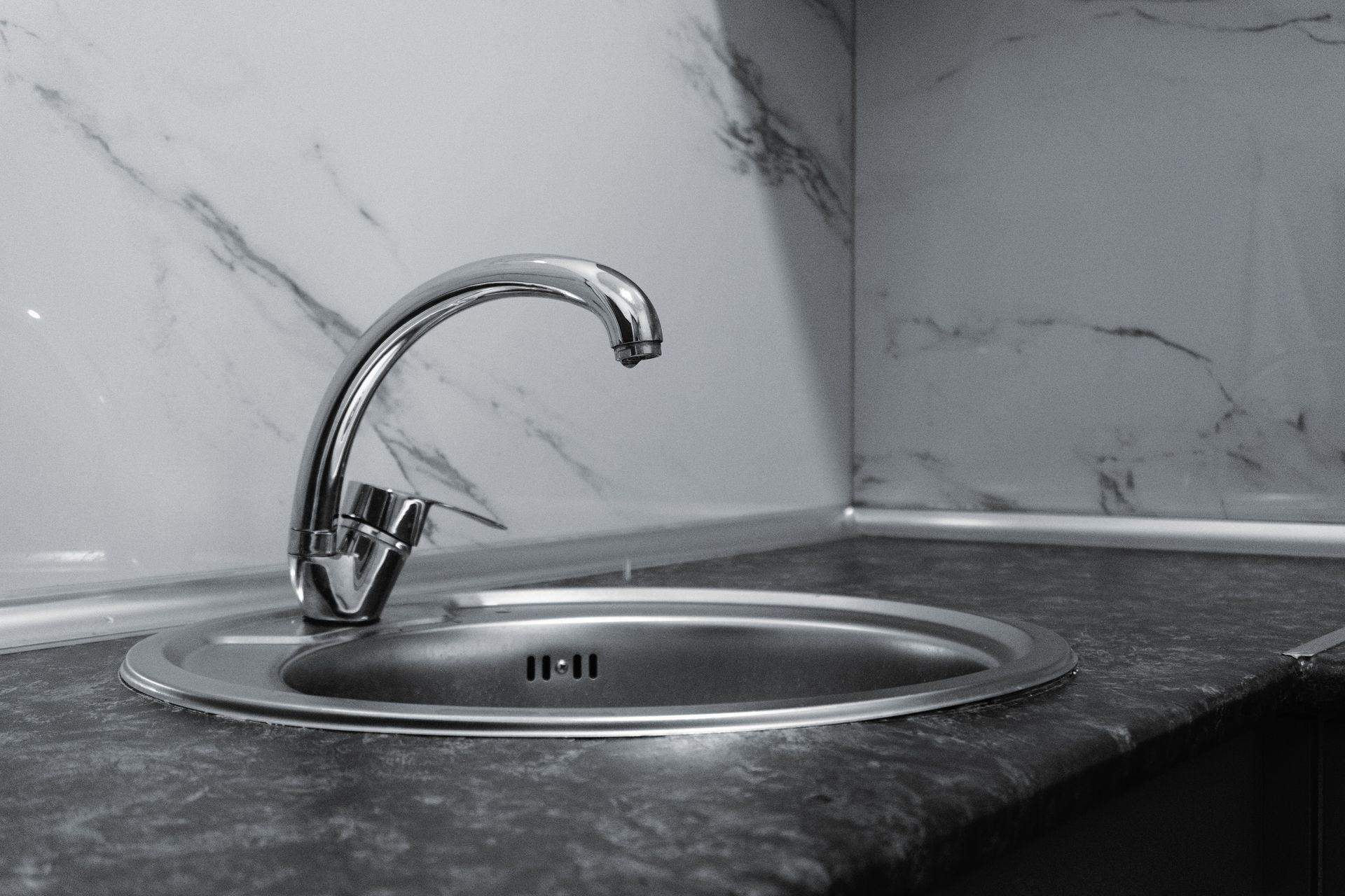 A stylish stainless steel kitchen faucet with a sleek and modern design set against a marble backsplash.